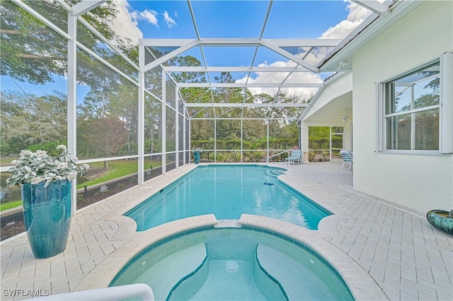 view of pool featuring glass enclosure, an in ground hot tub, ceiling fan, and a patio