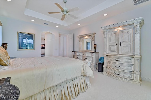 carpeted bedroom with ceiling fan and a tray ceiling