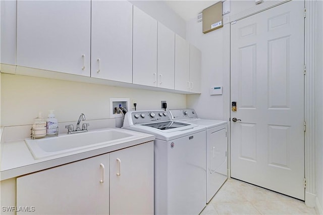 laundry area featuring cabinets, washer and clothes dryer, sink, and light tile patterned flooring