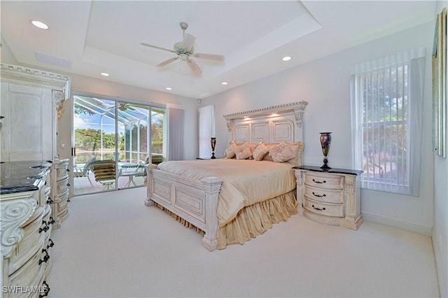 bedroom with ceiling fan, light colored carpet, a raised ceiling, and access to outside