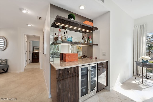 bar featuring wine cooler, dark brown cabinetry, and light tile patterned floors