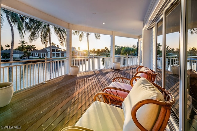 deck at dusk featuring a water view