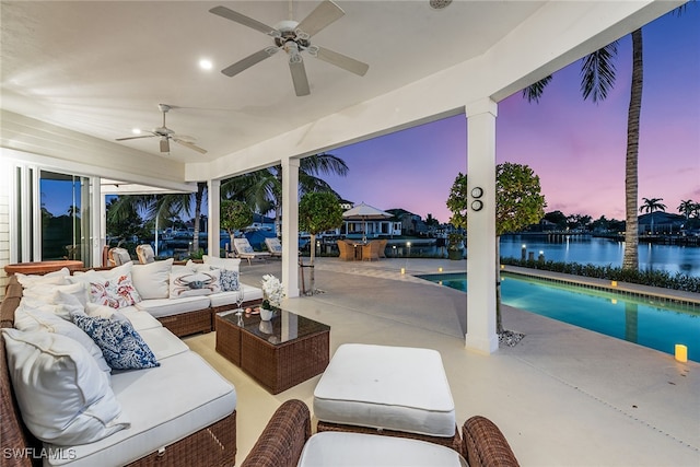 patio terrace at dusk featuring outdoor lounge area, a water view, and ceiling fan