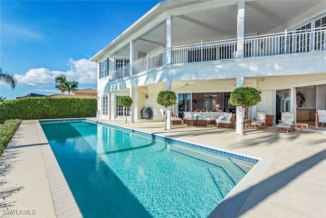 back of property featuring a balcony, outdoor lounge area, a fenced in pool, and a patio