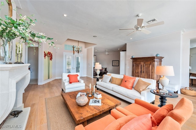 living room with ceiling fan with notable chandelier and light hardwood / wood-style flooring