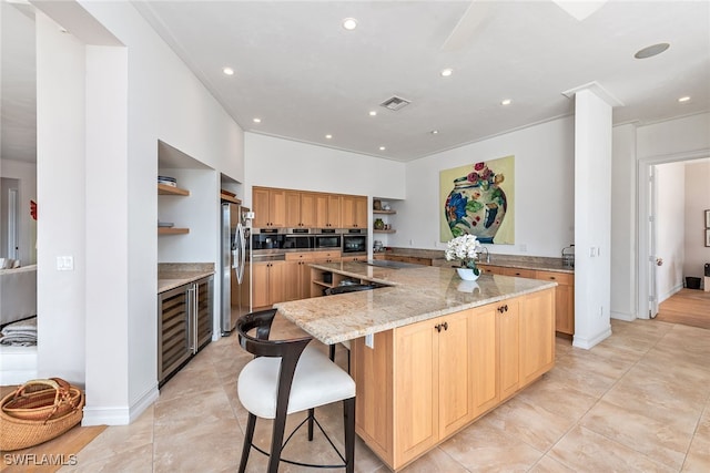 kitchen with appliances with stainless steel finishes, light stone countertops, a breakfast bar, beverage cooler, and a spacious island