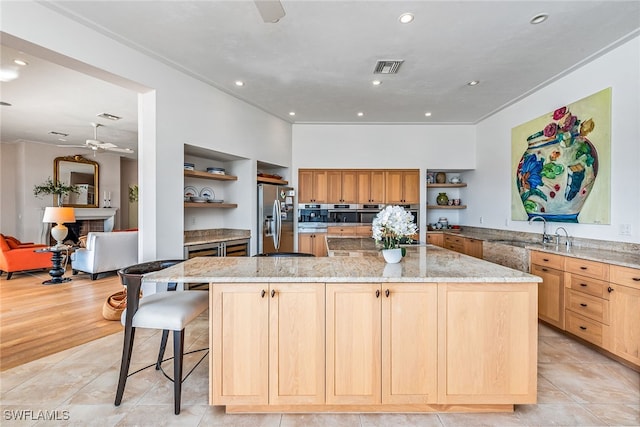 kitchen featuring a kitchen island, appliances with stainless steel finishes, light stone countertops, sink, and light hardwood / wood-style flooring