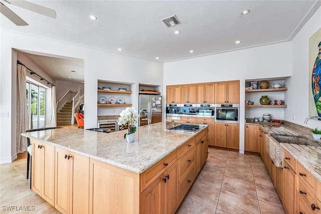 kitchen featuring a spacious island, appliances with stainless steel finishes, sink, and light stone countertops