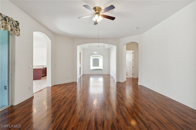 empty room featuring a wealth of natural light, dark hardwood / wood-style flooring, and ceiling fan