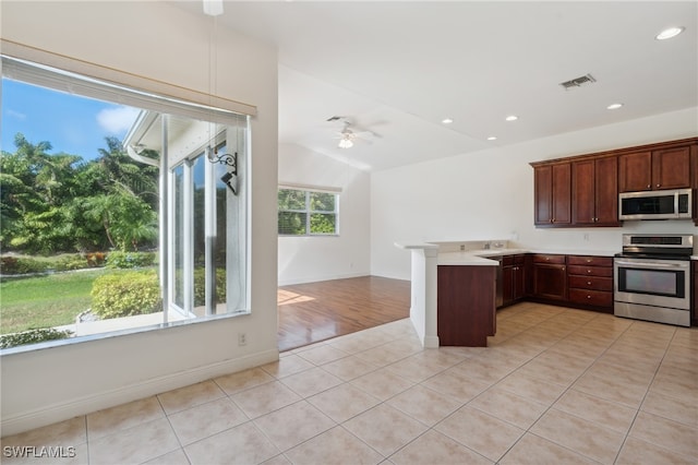 kitchen featuring ceiling fan, light tile patterned floors, stainless steel appliances, and vaulted ceiling