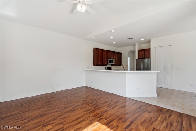 kitchen with kitchen peninsula, ceiling fan, light wood-type flooring, and appliances with stainless steel finishes