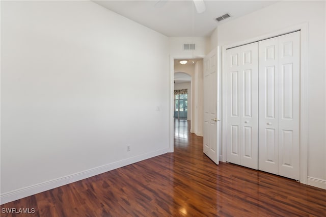 unfurnished bedroom with ceiling fan, dark hardwood / wood-style floors, and a closet