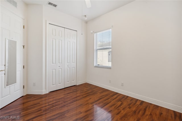 unfurnished bedroom featuring ceiling fan, a closet, and dark wood-type flooring