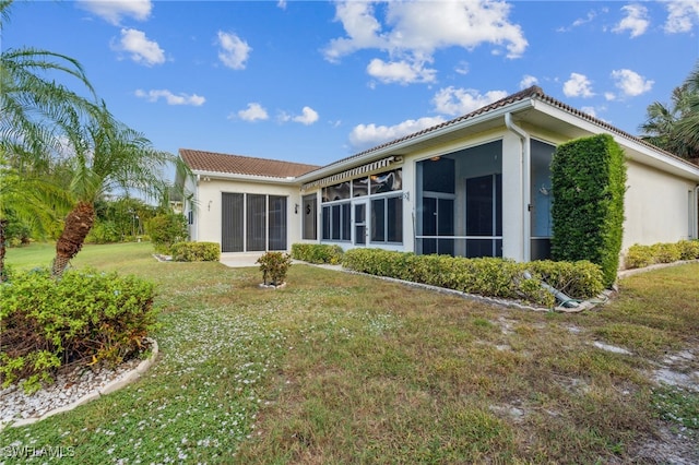 rear view of house featuring a lawn and a sunroom