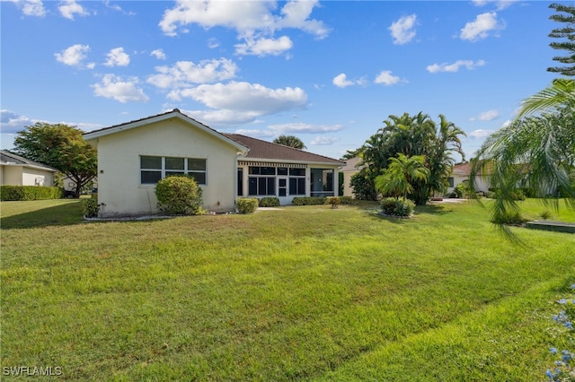 rear view of property featuring a lawn and a sunroom