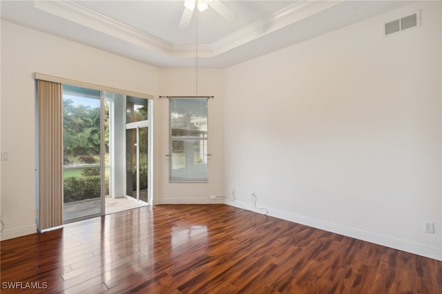 spare room with dark hardwood / wood-style floors, ceiling fan, crown molding, and a tray ceiling