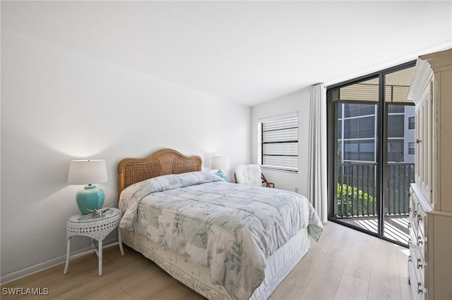 bedroom featuring light wood-type flooring, multiple windows, and access to outside