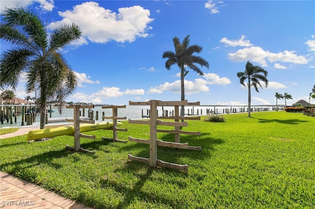 surrounding community with a water view, a yard, and a dock