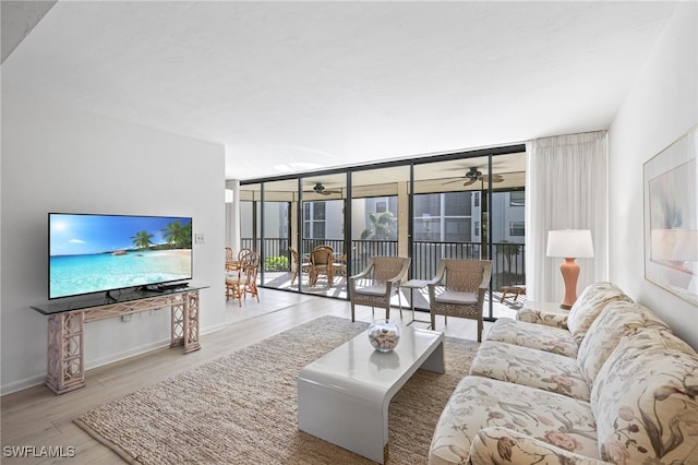 living room with a wall of windows, ceiling fan, and light hardwood / wood-style flooring