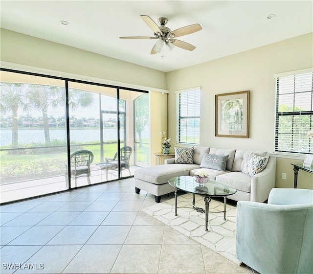 living room featuring a water view, a wealth of natural light, light tile patterned floors, and ceiling fan