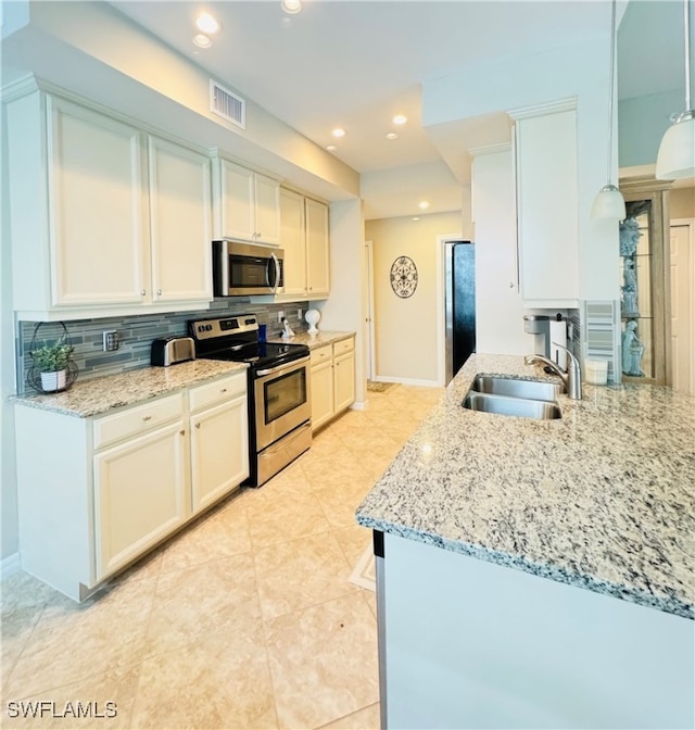 kitchen with white cabinetry, light stone counters, backsplash, and stainless steel appliances