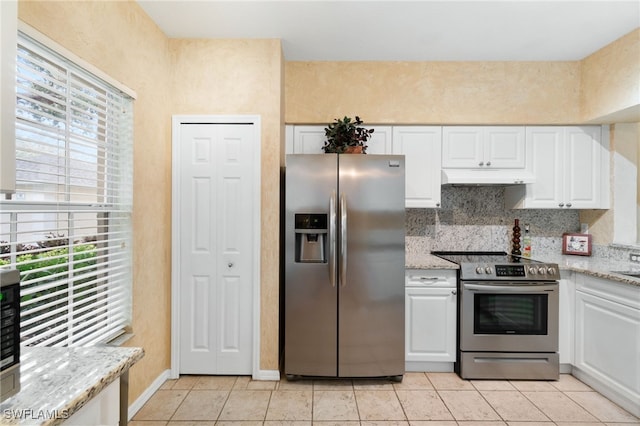 kitchen with light tile patterned flooring, light stone counters, white cabinetry, and appliances with stainless steel finishes