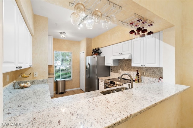 kitchen featuring kitchen peninsula, light stone counters, stainless steel appliances, sink, and white cabinets