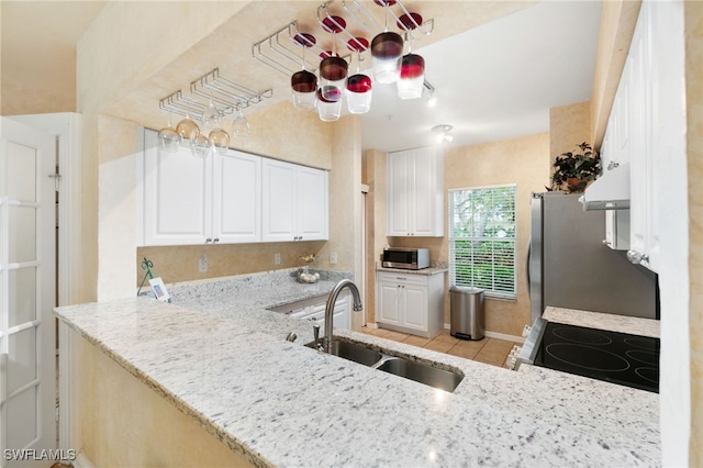 kitchen featuring appliances with stainless steel finishes, sink, range hood, white cabinets, and light tile patterned flooring