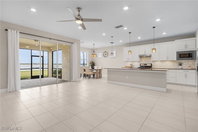 kitchen featuring pendant lighting, stainless steel appliances, white cabinetry, and a kitchen island with sink