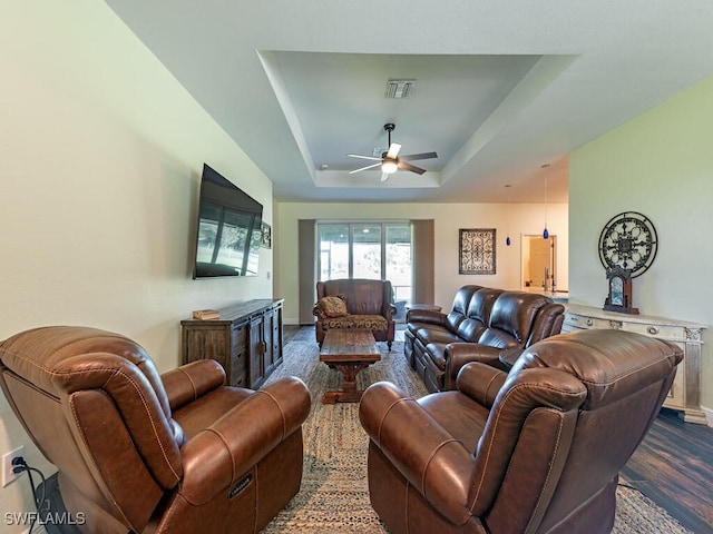 living room with a tray ceiling, ceiling fan, and dark hardwood / wood-style floors