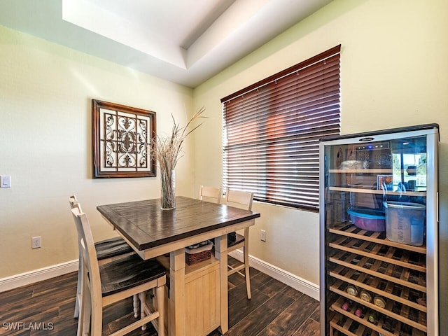 dining room featuring dark hardwood / wood-style floors, beverage cooler, and a raised ceiling