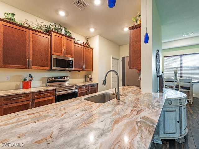 kitchen with stainless steel appliances, sink, light stone counters, a kitchen bar, and dark hardwood / wood-style flooring