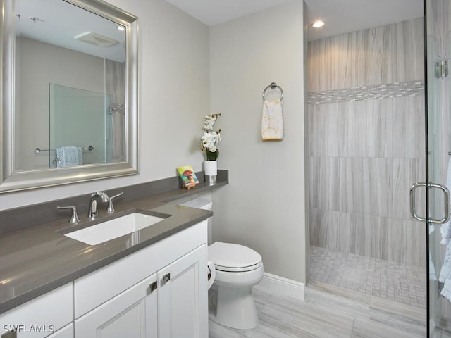 bathroom with tiled shower, vanity, hardwood / wood-style flooring, and toilet