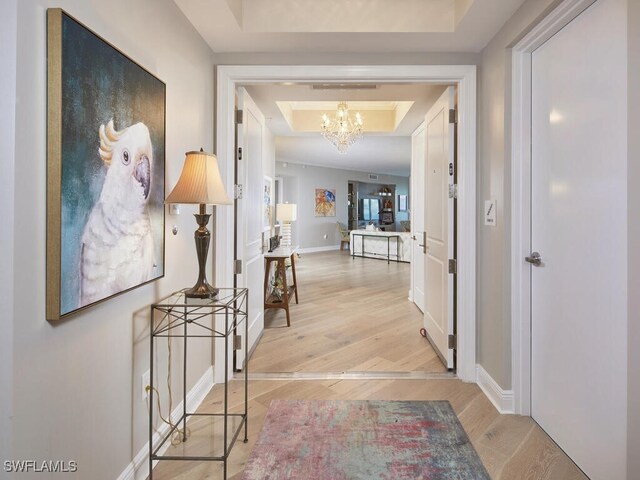 4800 Pelican Colony Blvd Unit 803, Bonita Springs, FL 34134 - hallway with a tray ceiling, light wood-style flooring, and a chandelier
