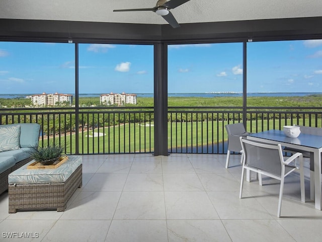 sunroom with a water view and ceiling fan