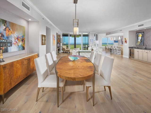 dining space with light hardwood / wood-style floors, beverage cooler, and crown molding