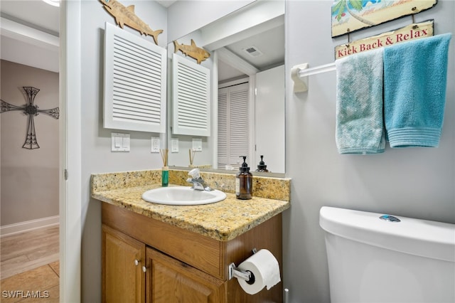 bathroom with hardwood / wood-style flooring, vanity, and toilet