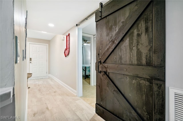 hallway with a barn door and light hardwood / wood-style floors