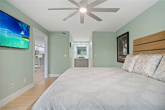 bedroom featuring connected bathroom, ceiling fan, sink, and hardwood / wood-style flooring