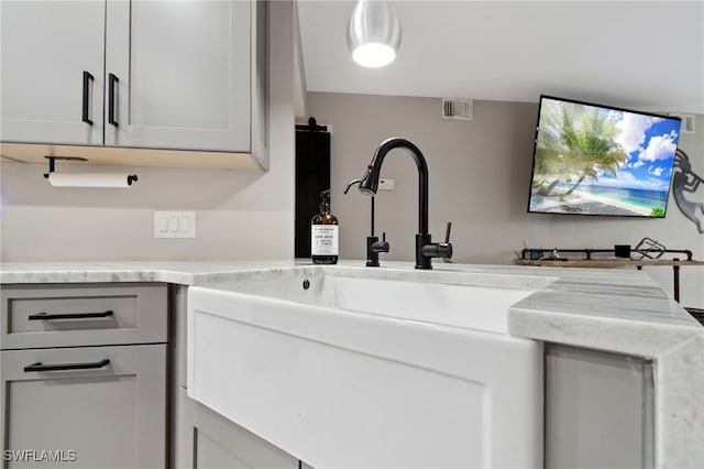 interior space with white cabinets, light stone counters, and sink