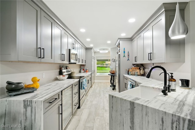 kitchen with appliances with stainless steel finishes, light hardwood / wood-style floors, light stone counters, and sink