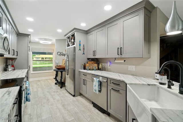 kitchen with sink, light stone countertops, stainless steel appliances, and light hardwood / wood-style flooring