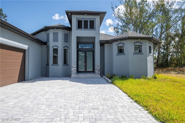 view of front facade with a garage, french doors, and a front lawn