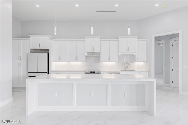 kitchen with decorative light fixtures, white cabinetry, white refrigerator, and a large island