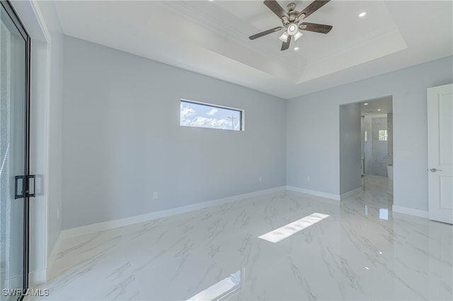 empty room with crown molding, ceiling fan, and a raised ceiling