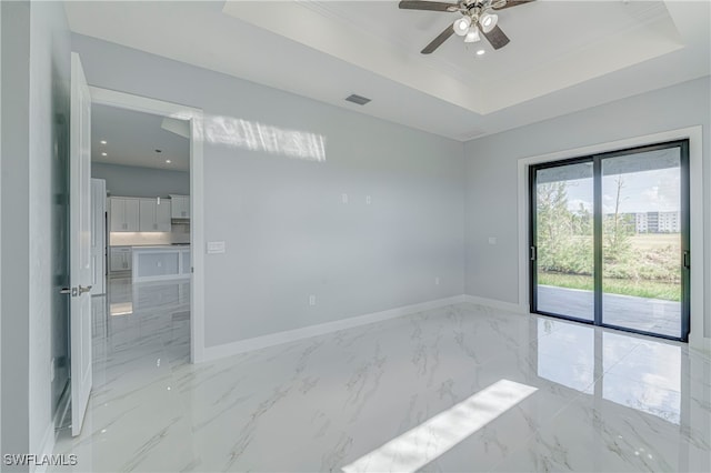 spare room featuring ceiling fan and a raised ceiling