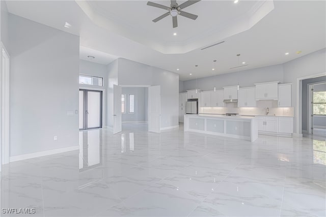 unfurnished living room with sink, a high ceiling, a raised ceiling, and crown molding