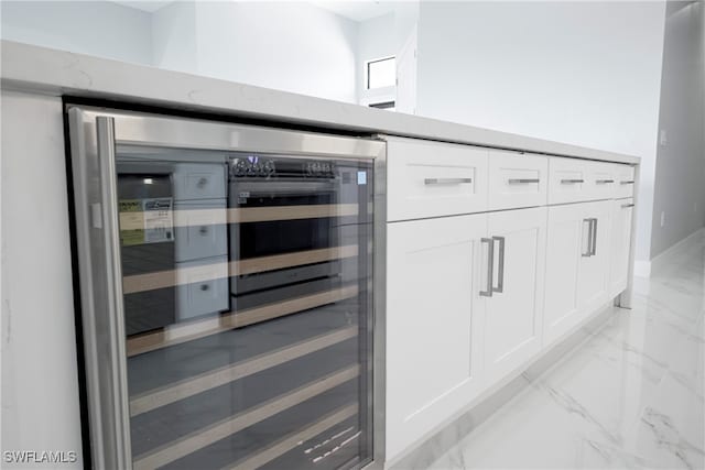 details featuring white cabinetry, beverage cooler, and light stone countertops