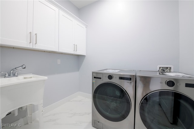 clothes washing area featuring cabinets and washer and clothes dryer