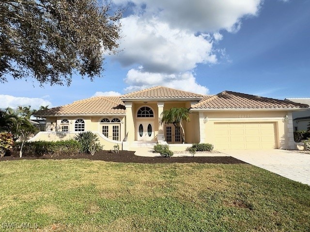 mediterranean / spanish-style home featuring a tile roof, stucco siding, concrete driveway, an attached garage, and a front yard